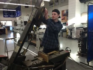 Nate cuts foot-long sections of tubing for the spaces for the elevator system