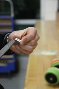 David deburrs a wire clamp that he has previously milled